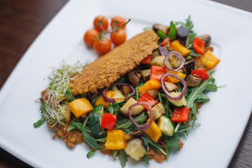 a white plate with a salad with vegetables on it at Biała Akacja Resort & Business in Prudnik