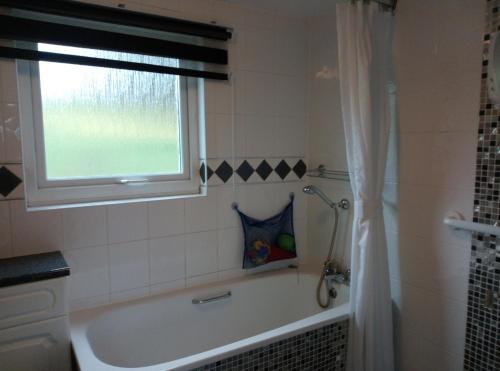 a bathroom with a bath tub and a window at Anstey Cove in Bembridge