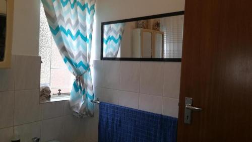 a bathroom with a mirror and a blue shower curtain at Bottie's Rock in Pretoria