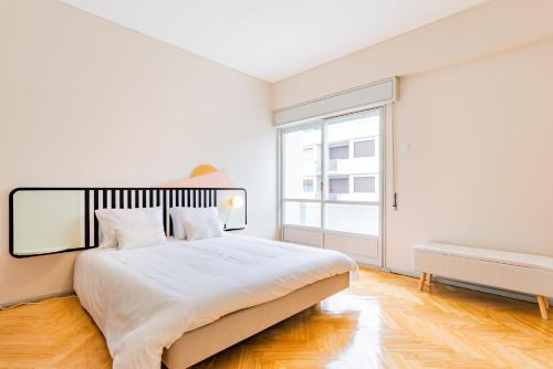a white bedroom with a large bed and a window at INCREDIBLE DUPLEX PENTHOUSE & TERRACES & Parking in Porto