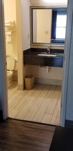 a bathroom with a sink and a toilet and a mirror at Best Inn Formerly Known as M Star Hotel in Chickasaw