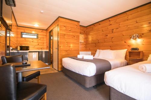 a hotel room with two beds and a desk at Parklands Motorlodge & Holiday Park in Turangi