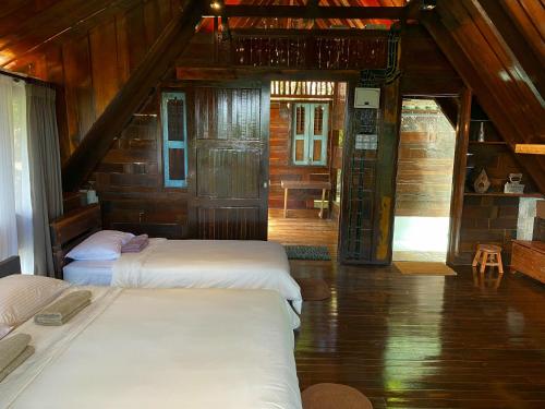 two beds in a room with wooden walls at Langit Rimba Resort in Seremban
