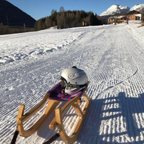 a helmet is sitting on a sled in the snow at Bucherhof in Obsteig
