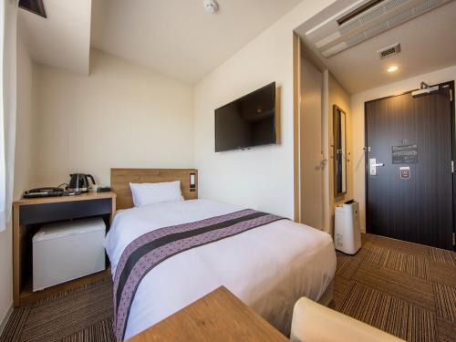 a hotel room with a bed and a tv at Tosei Hotel & Seminar Makuhari in Narashino