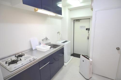 uma cozinha com armários azuis e um lavatório em Comfort CUBE PHOENIX MIYAZAKI em Miyazaki