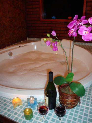 a bath tub with a bottle of wine and flowers at Pousada Magia da Montanha in Visconde De Maua