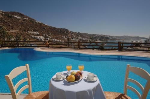 a table with a plate of fruit next to a swimming pool at Paradision Hotel in Tourlos