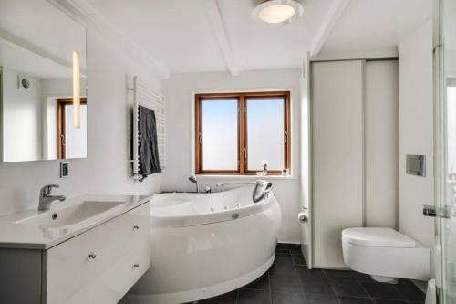 a white bathroom with a tub and a sink and a toilet at Marieshus in Holstebro