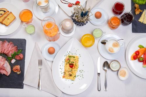 a white table with plates of food on it at Adler Inn Tyrol Mountain Resort SUPERIOR in Tux