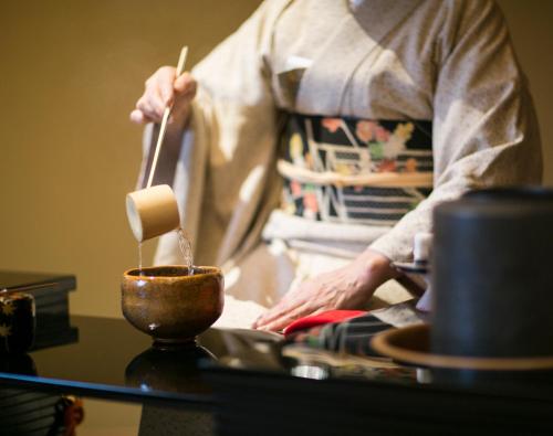 a person is stirring a pot with a chopstick at The Okura Tokyo in Tokyo