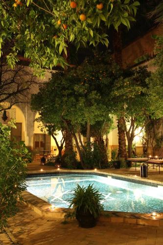 a swimming pool in a courtyard with trees and lights at Riad Laila in Marrakech