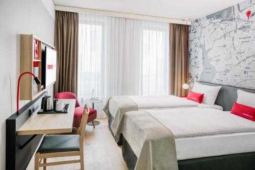 a hotel room with two beds and a desk at IntercityHotel Hamburg-Barmbek in Hamburg