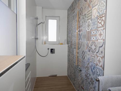 a bathroom with a shower and a tile wall at 16Lilien Apartmentwohnung Gartenblick in Waiblingen