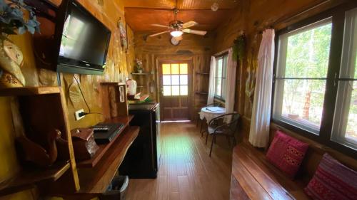 ein Wohnzimmer mit einem TV und ein Zimmer mit einem Tisch in der Unterkunft Saiyok River House in Sai Yok