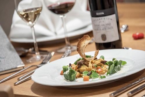 a plate of food on a table with a bottle of wine at Naturhotel Runa in Rodengo