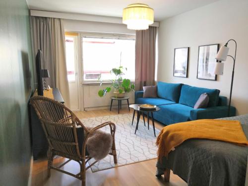 a living room with a blue couch and a bed at City Apartment Savonkatu in Kuopio