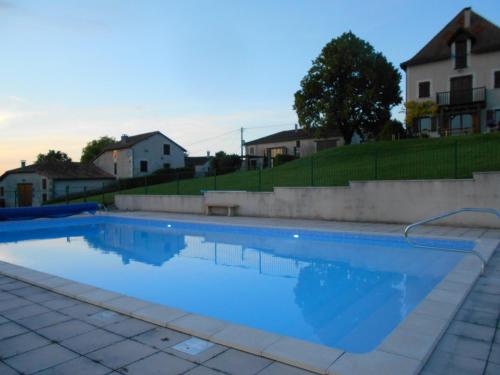 une piscine bleue avec une maison en arrière-plan dans l'établissement Coutancie, à Nanteuil-Auriac-de-Bourzac