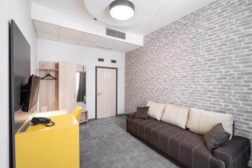 a living room with a couch and a brick wall at ADEO HOTEL Sport & SPA in Ruse