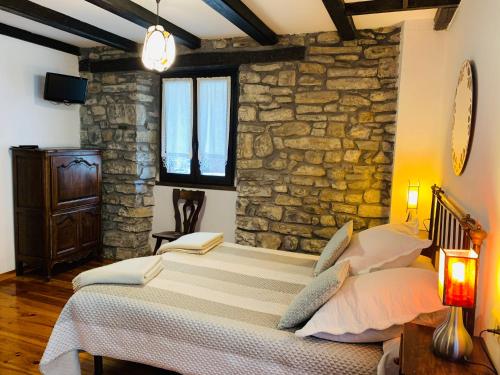 a bedroom with a bed and a stone wall at Argonz Etxea in Urzainqui