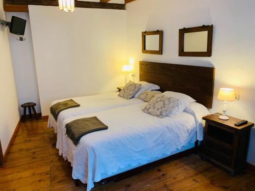 a bedroom with a large white bed with two lamps at Argonz Etxea in Urzainqui