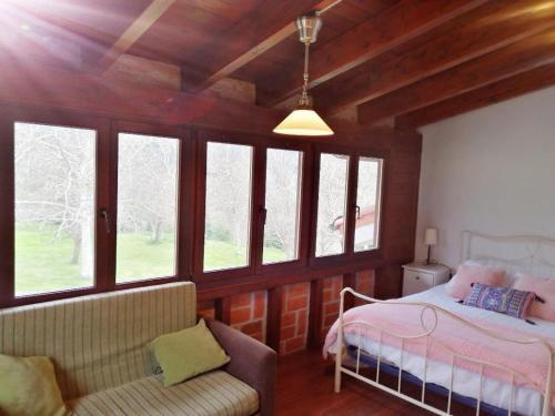 a bedroom with a bed and a couch and windows at La Fragua del Canajal apartamentos in San Cosme