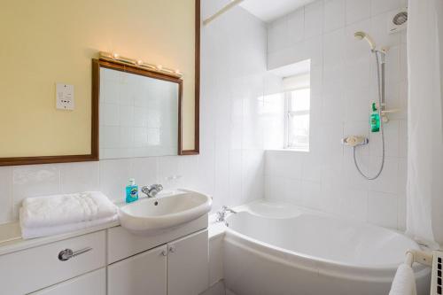 a white bathroom with a sink and a bath tub at The Queens Head Kettlesing in Harrogate