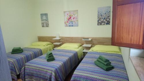 three beds in a room with green pillows on them at Casetta Gaia in Latina