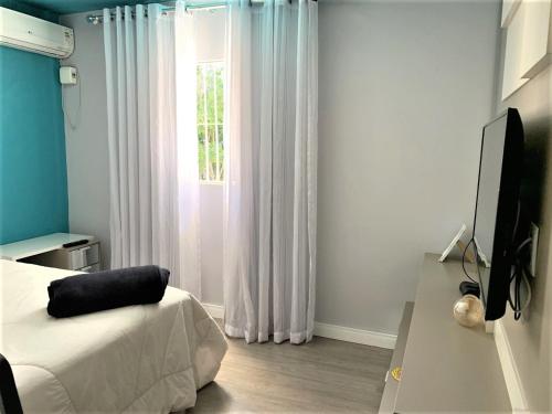 1 dormitorio con 1 cama, TV y ventana en Mello's House, en Curitiba