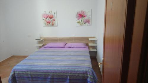 a bed in a room with two pictures on the wall at Casetta Gaia in Latina