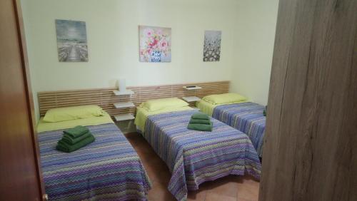 1 dormitorio con 3 camas con almohadas verdes en Casetta Gaia en Latina