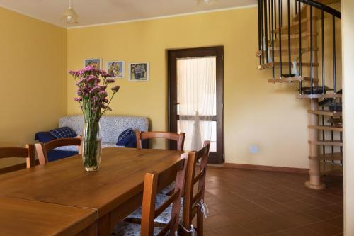 a dining room table with a vase of flowers on it at Terremesu a Castiadas Villasimius Costa Rei in Castiadas