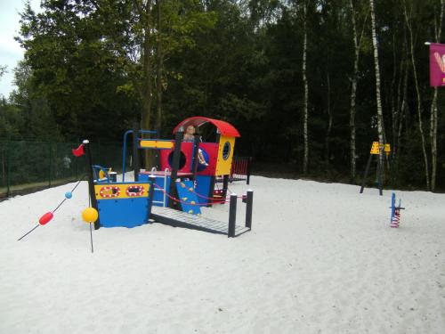 um parque infantil na areia com uma criança sobre ele em Camping De Binnenvaart Superior Chalet em Aan de Wolfsberg