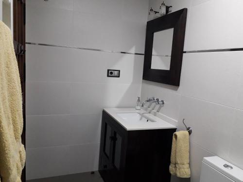 a white bathroom with a sink and a mirror at Vía Caparra Superior in Oliva de Plasencia