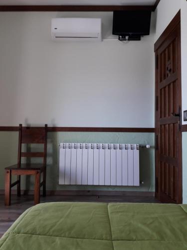 a bedroom with a bed and a chair and a television at Vía Caparra Superior in Oliva de Plasencia