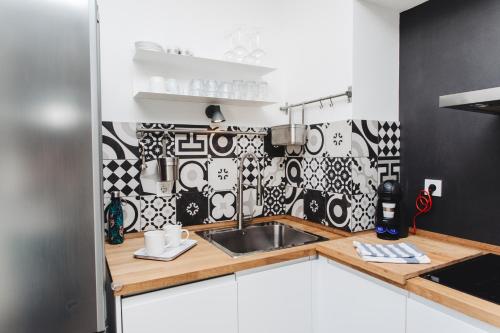 eine Küche mit einem Waschbecken und schwarzen und weißen Fliesen in der Unterkunft 3in1 Holiday Home in Rogoznica