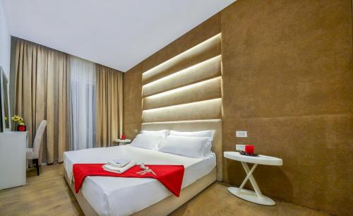 um quarto com uma grande cama branca e um cobertor vermelho em Hotel Bora Bora velipoja em Velipojë