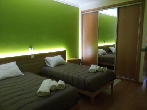a green room with two beds and a mirror at Casa da Floresta in Santiago da Guarda