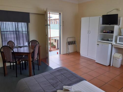 a room with a bed and a table and a kitchen at Inverell Motel in Inverell