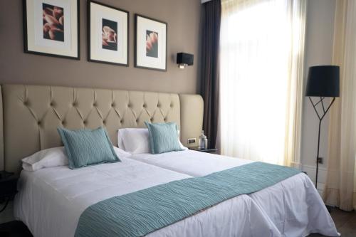een slaapkamer met een groot wit bed met blauwe kussens bij Hotel Bienestar Termas De Vizela in Vizela