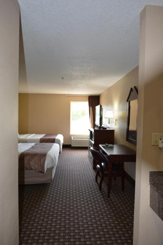 a hotel room with two beds and a desk and a window at Jameson Inn and Suites Hazelhurst in Hazlehurst