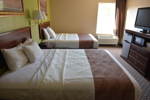 a hotel room with two beds and a flat screen tv at Jameson Inn and Suites Hazelhurst in Hazlehurst