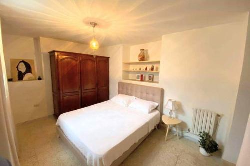 a bedroom with a white bed and a wooden cabinet at Cosy 2 pièces charmant et spacieux in Tunis