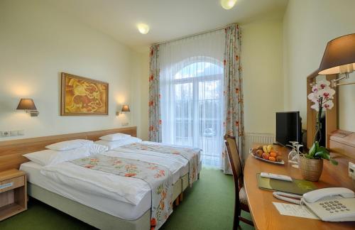 a bedroom with a bed and a desk with a telephone at Hotel Kiss in Tata