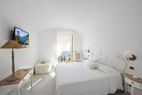 a white bedroom with a white bed and a window at La Maurella in Praiano