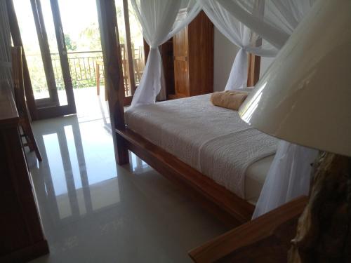 a bedroom with a bed with a canopy at Suryadina Guest House in Ubud