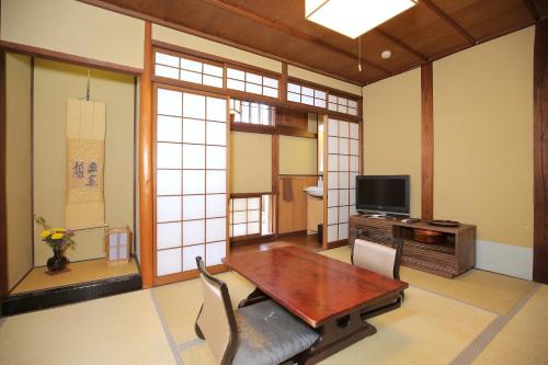a living room with a wooden table and a tv at Ryori Ryokan Tsurugata in Kurashiki