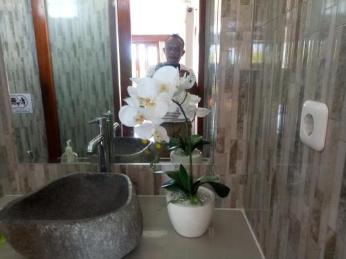 a man standing in front of a mirror in a bathroom at Suryadina Guest House in Ubud