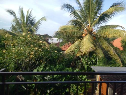 a view from the balcony of a resort with palm trees at Suryadina Guest House in Ubud