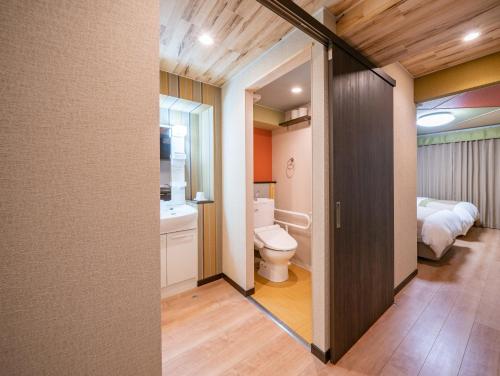 a bathroom with a toilet and a bed in a room at Residence Hotel Takayama Station in Takayama